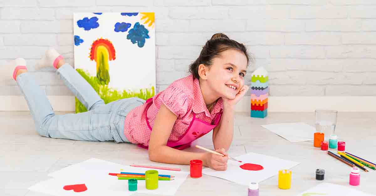 girl lying on floor painting on white paper with red brush