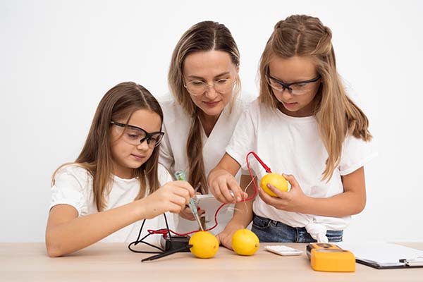 Girls doing science experiments with female teacher and lemons
