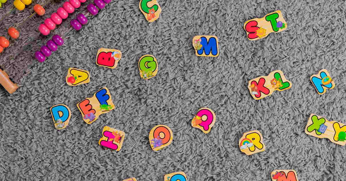 Bright and colorful alphabet puzzle pieces scattered on a carpet with a wooden abacus on the side