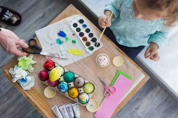Kid decorating eggs for easter using art and craft kit 