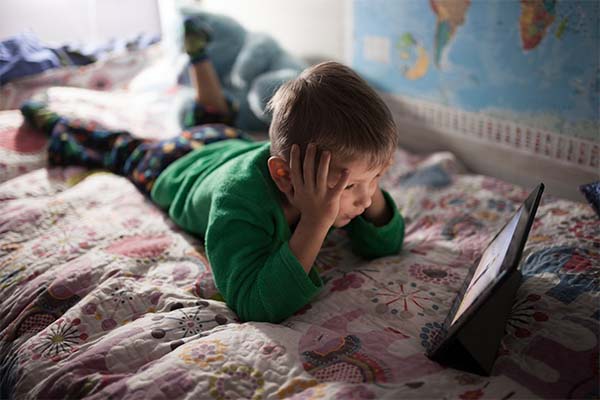 Boy watching movie on tab laying on bed