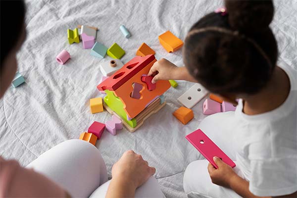 Teacher teaching shapes to toddlers through puzzle game 