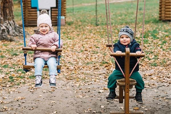 Toddler children swinging and enjoying outdoor games in backyard