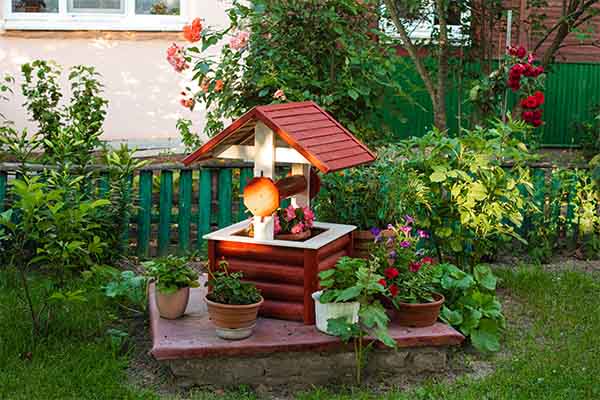 small garden in the backyard. Fake well with potted flowers.