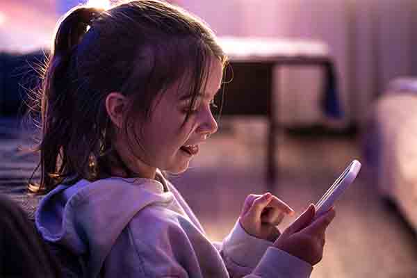 A little girl uses a smartphone while sitting in her room