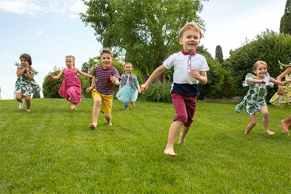 Kids fashion concept. The group of teen boys and girls running at park.