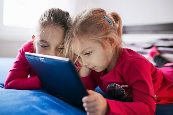 Girls looking at tablet on bed