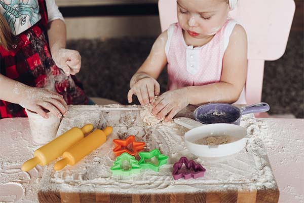 Cute girls playing with dough at kitchen