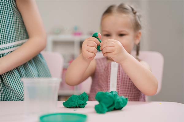 little girl moulds from plasticine on table
