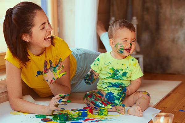 Mother and son enjoying messy play activity with paint 